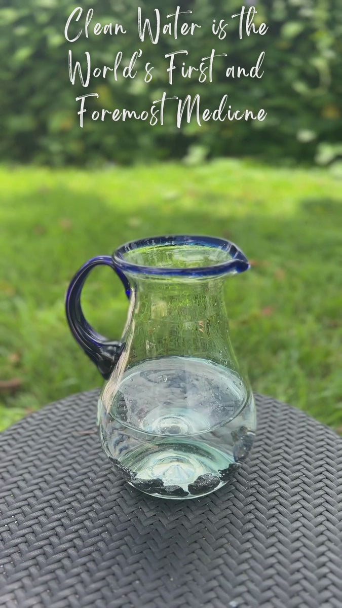 Large shungite rocks dropped into a pitcher of drinking water and then poured into a drinking glass