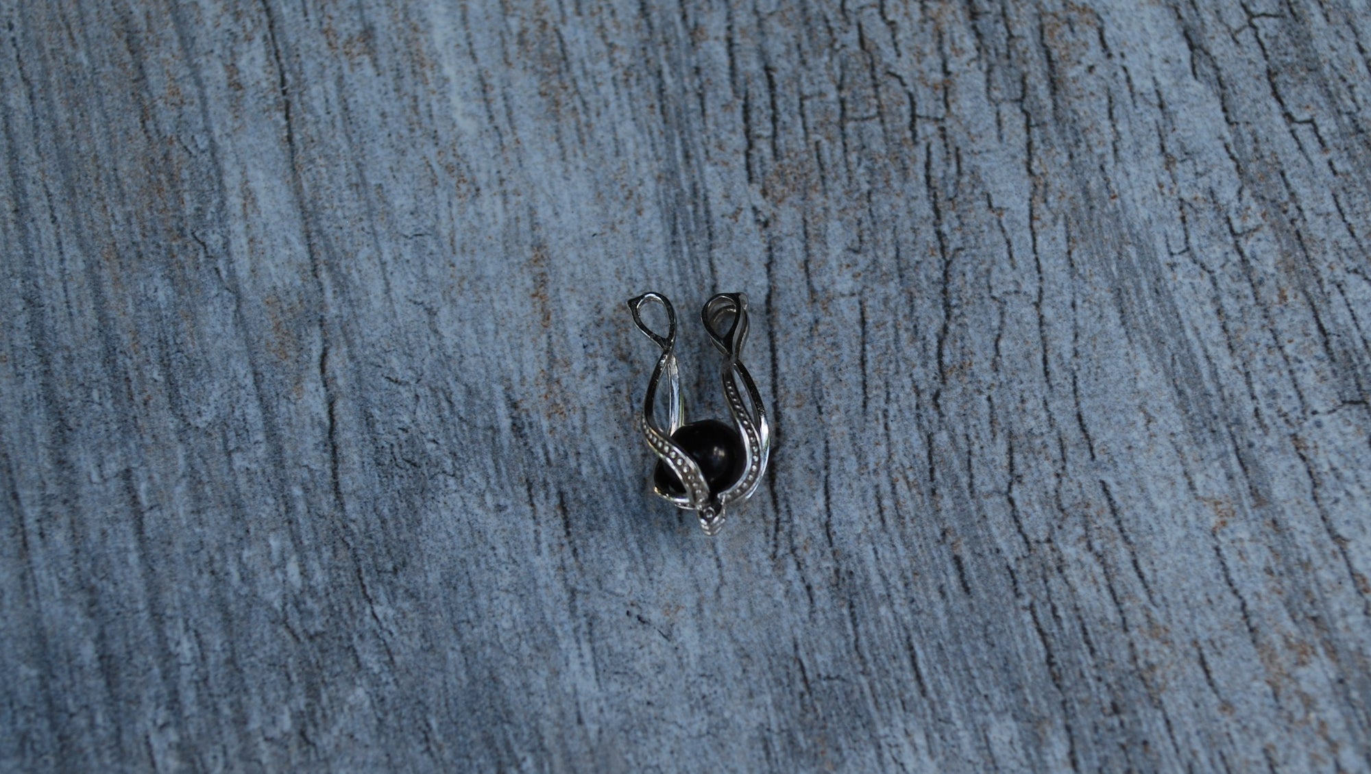 Sterling silver cage with a 6mm shungite stone open and ready to change out the stone inside, with 9 different options