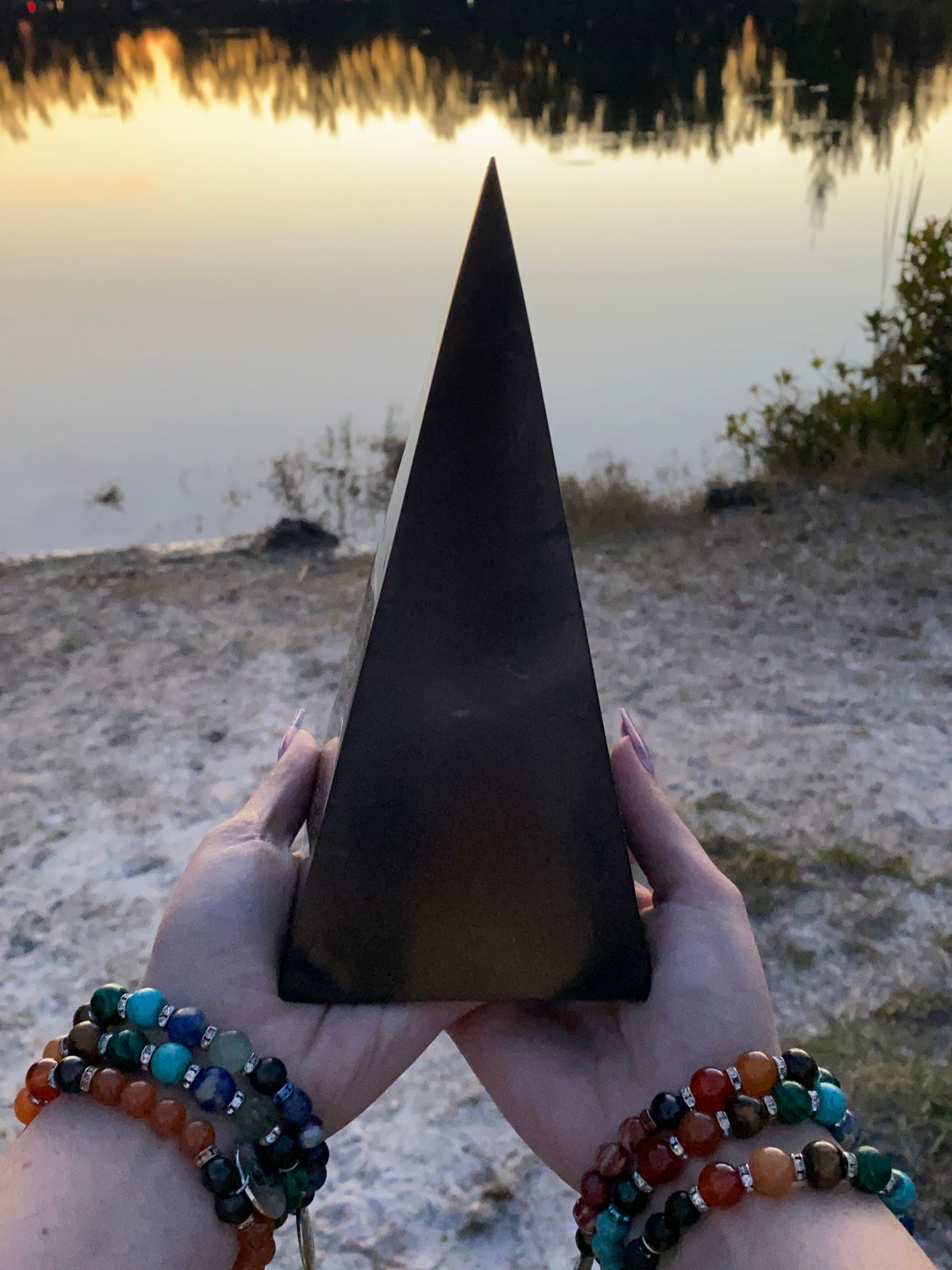 7.5-Inch Polished Reiki Charged Shungite Power Pyramid compared to the size of a woman's hands