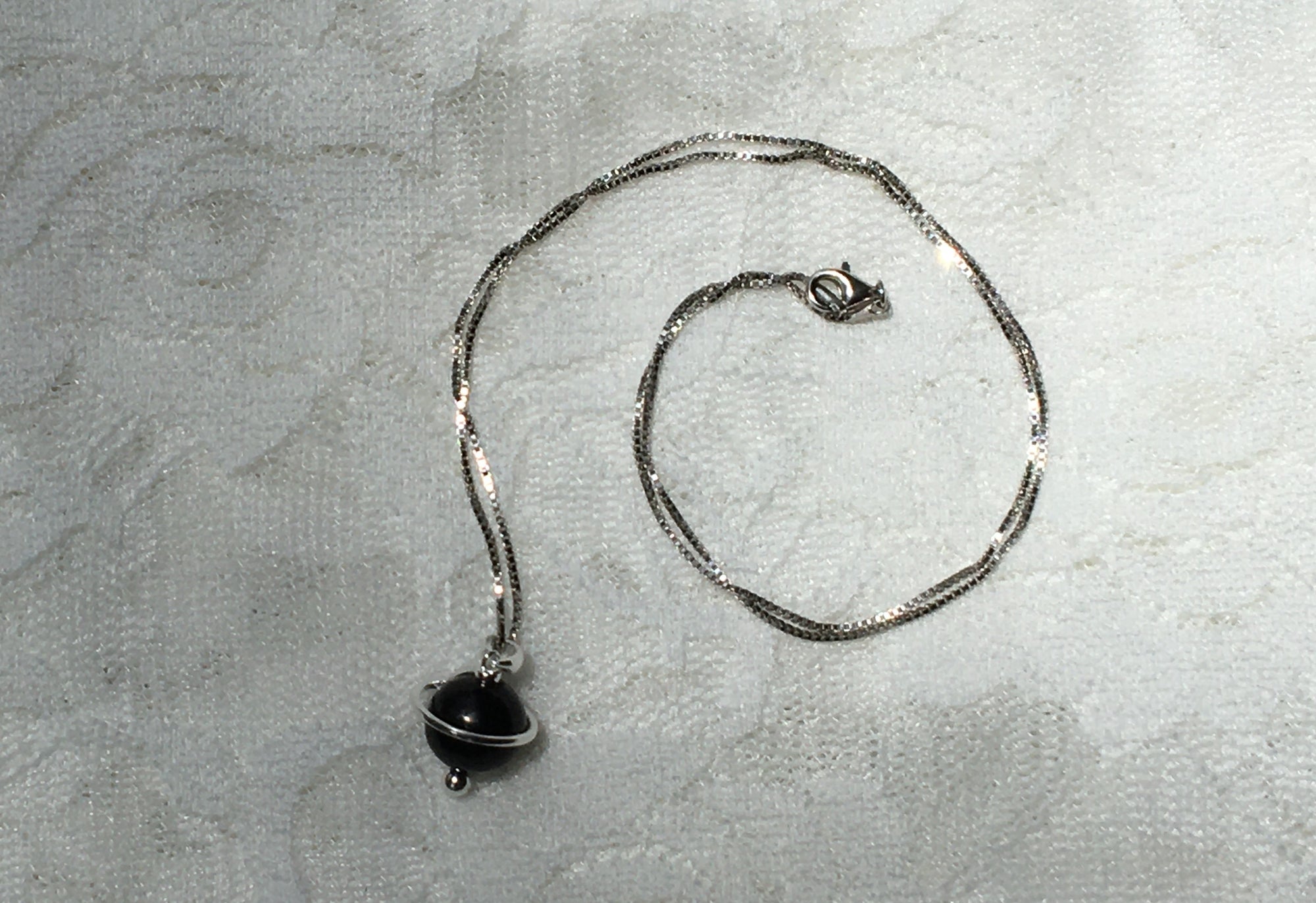 Young woman wearing the Shungite Orbit Pendant on a sterling silver chain