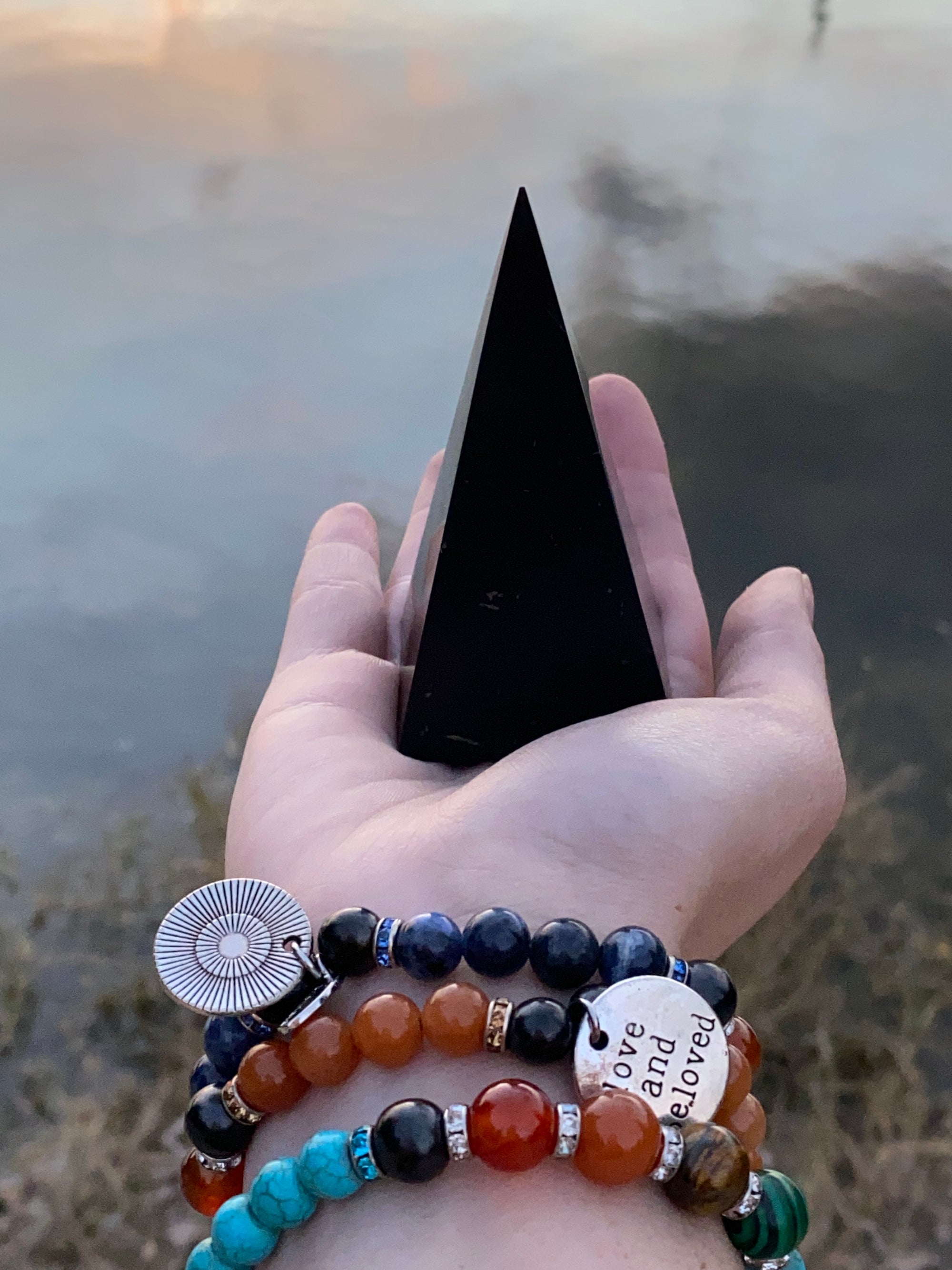  3.5-Inch Polished Reiki Charged Shungite Power Pyramid compared to the size of a woman's hands