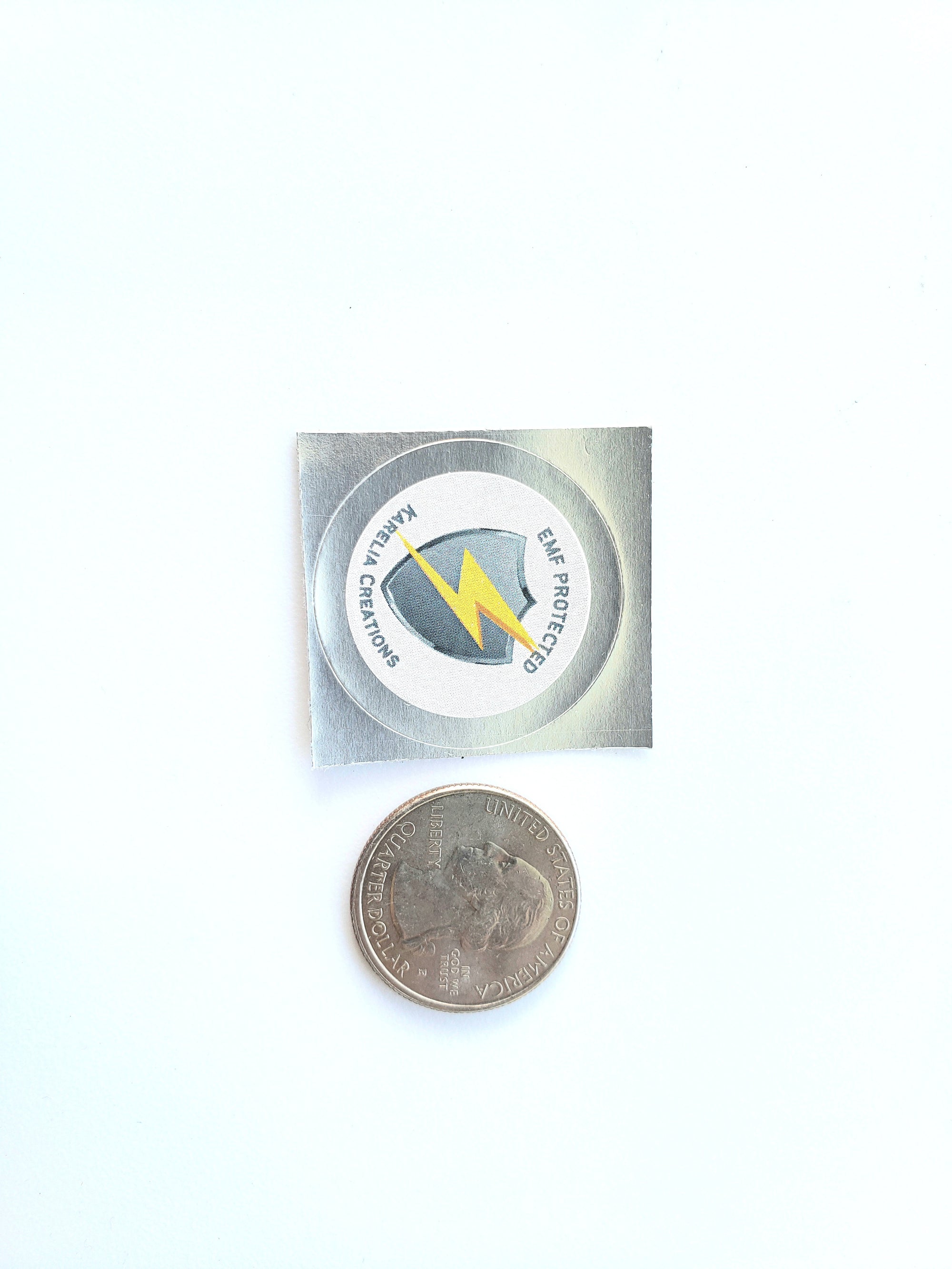 EMF Protected shield cellphone sticker with shungite powder, compared to the size of a quarter