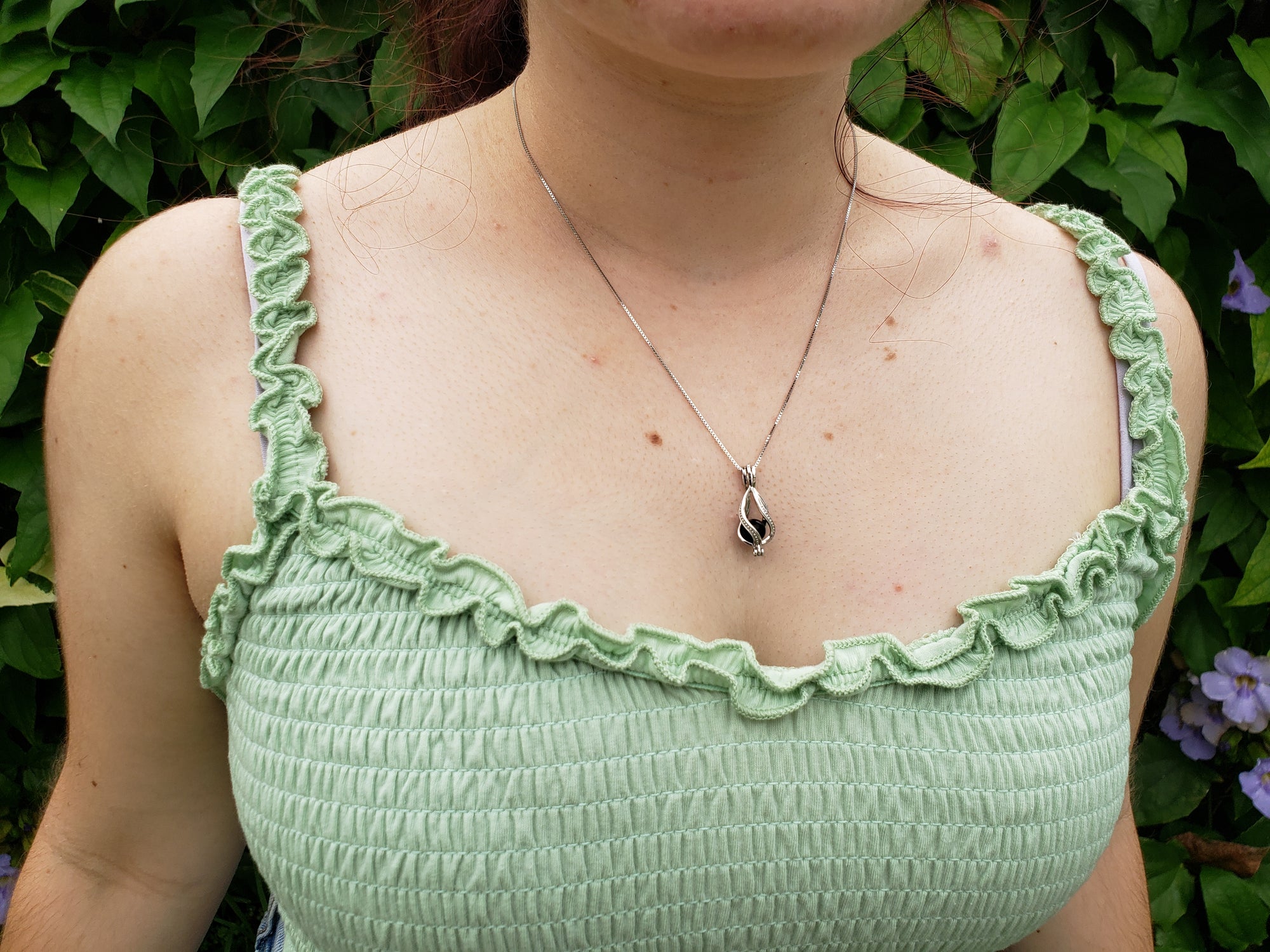 Young woman wearing the sterling silver cage pendant with the classic 6mm shungite bead