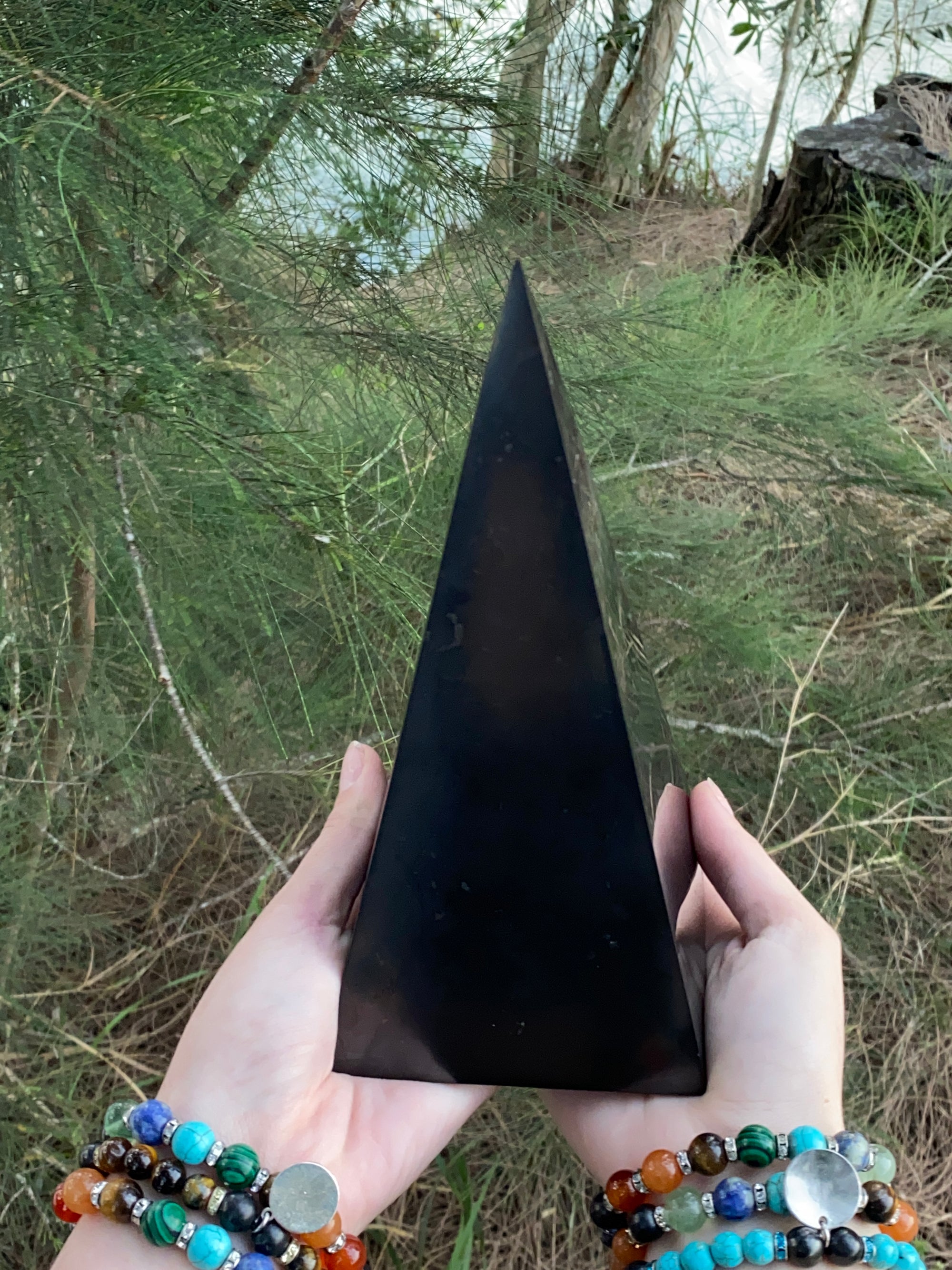 7.5-Inch Polished Reiki Charged Shungite Power Pyramid compared to the size of a woman's hands